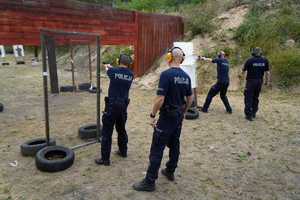 policjanci biegną przez przeszkody i strzelają z pistoletów do tarcz na strzelnicy