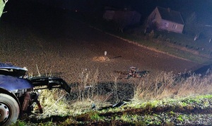 Na zdjęciu samochód osobowy rozbity na drzewie. Wokół stoją policjanci, straży, karetka pogotowia, radiowóz.