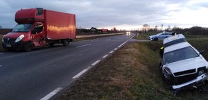 fotografia auta z rozbitą szybą czołową w tle radiowóz policji, fotografie z miejsca wypadku drogowego, srebrne auto przewrócone w przydrożnym rowie