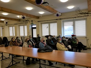 Na zdjęciach sala konferencyjna, na krzesłach grupa seniorów przysłuchuje się prezentacji przedstawianej przez umundurowanego policjanta oraz strażaka. Na ścianie wyświetlana jest prezentacja multimedialna.